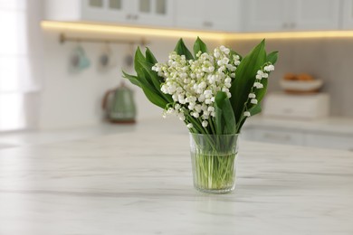 Photo of Bouquet of beautiful lily-of-the-valley on white marble table in kitchen