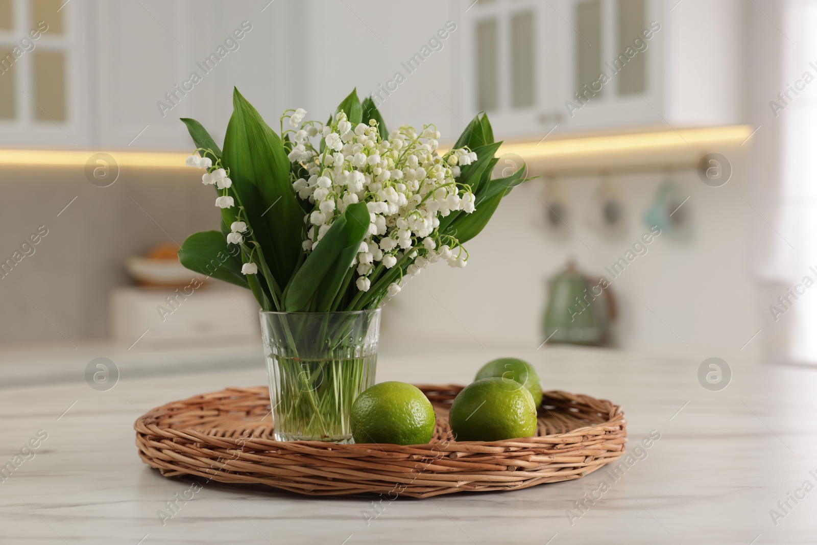 Bouquet of beautiful lily-of-the-valley and limes on white marble table in kitchen Photo of Bouquet of beautiful lily-of-the-valley and limes on white marble table in kitchen
