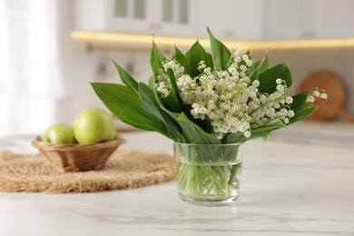Photo of Bouquet of beautiful lily-of-the-valley on white marble table in kitchen, closeup