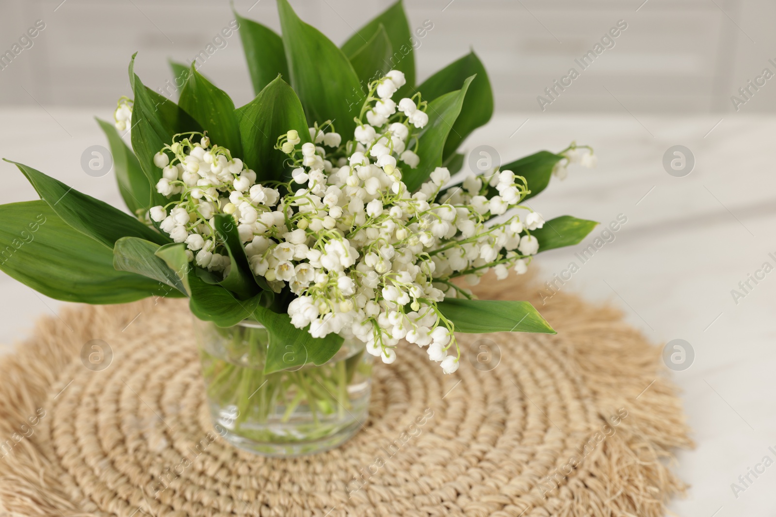 Bouquet of beautiful lily-of-the-valley on white table indoors, closeup Photo of Bouquet of beautiful lily-of-the-valley on white table indoors, closeup