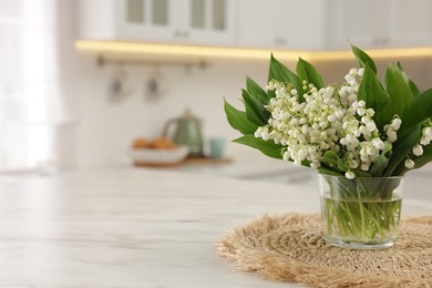 Photo of Bouquet of beautiful lily-of-the-valley on white marble table in kitchen, closeup. Space for text