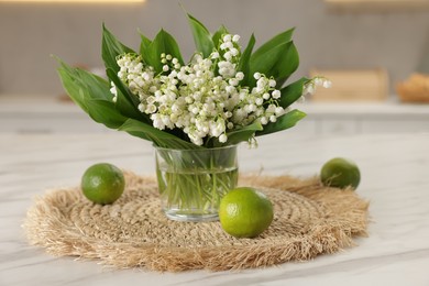 Photo of Bouquet of beautiful lily-of-the-valley and limes on white marble table indoors, closeup
