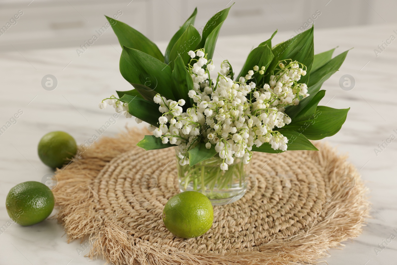 Bouquet of beautiful lily-of-the-valley and limes on white marble table indoors, closeup Photo of Bouquet of beautiful lily-of-the-valley and limes on white marble table indoors, closeup