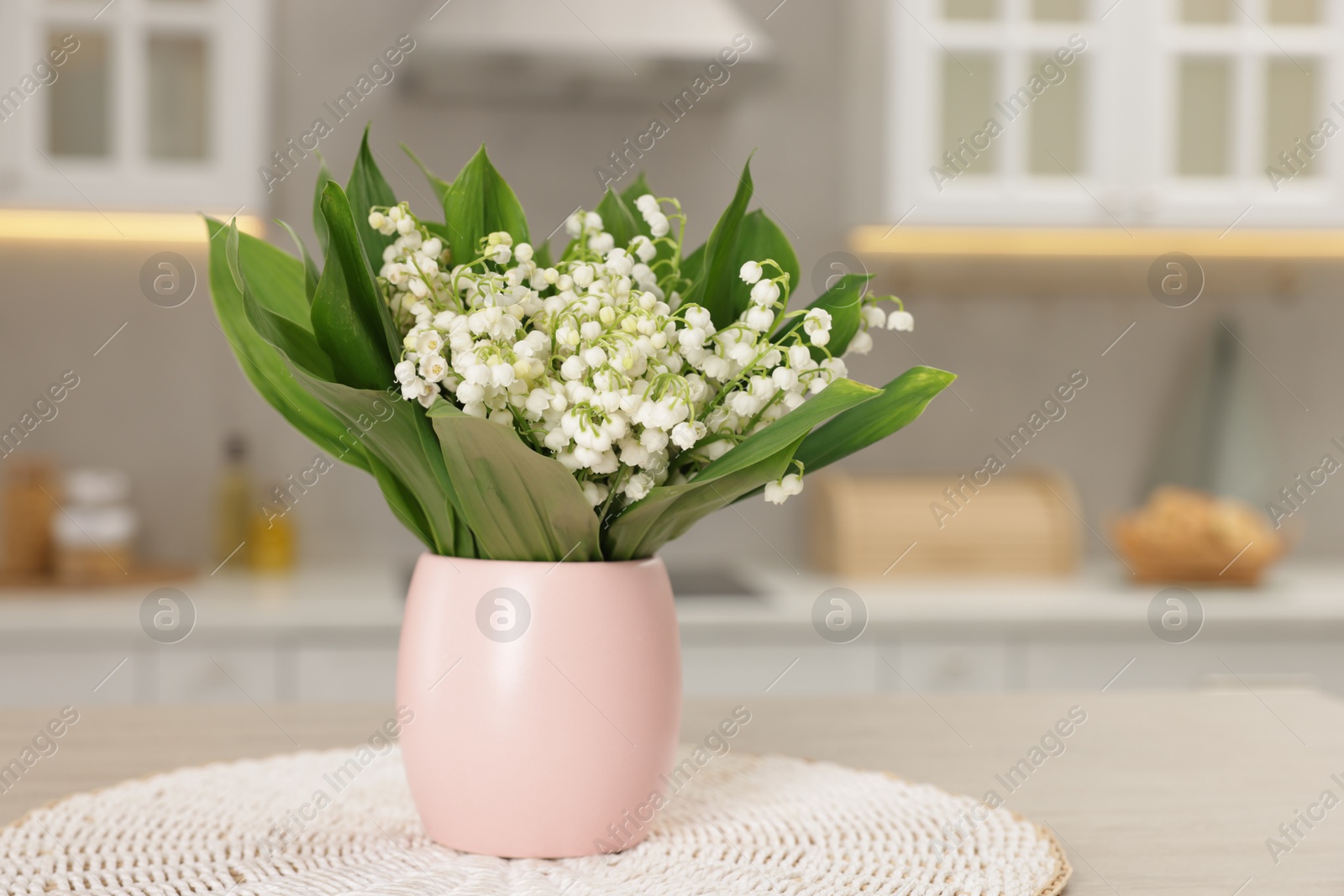 Bouquet of beautiful lily-of-the-valley on wooden table in kitchen, closeup Photo of Bouquet of beautiful lily-of-the-valley on wooden table in kitchen, closeup