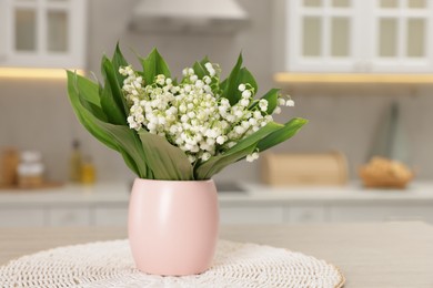 Photo of Bouquet of beautiful lily-of-the-valley on wooden table in kitchen, closeup