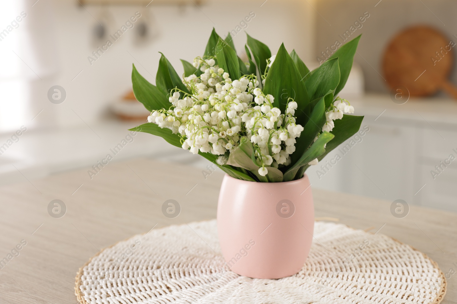 Bouquet of beautiful lily-of-the-valley on wooden table in kitchen, closeup Photo of Bouquet of beautiful lily-of-the-valley on wooden table in kitchen, closeup