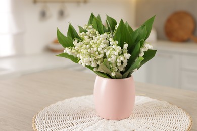 Photo of Bouquet of beautiful lily-of-the-valley on wooden table in kitchen, closeup