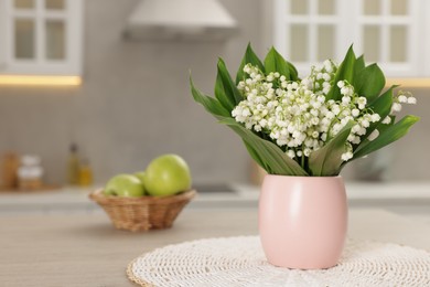 Photo of Bouquet of beautiful lily-of-the-valley on wooden table in kitchen, closeup