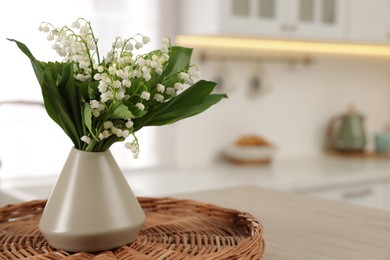 Photo of Bouquet of beautiful lily-of-the-valley in vase on table in kitchen, closeup. Space for text