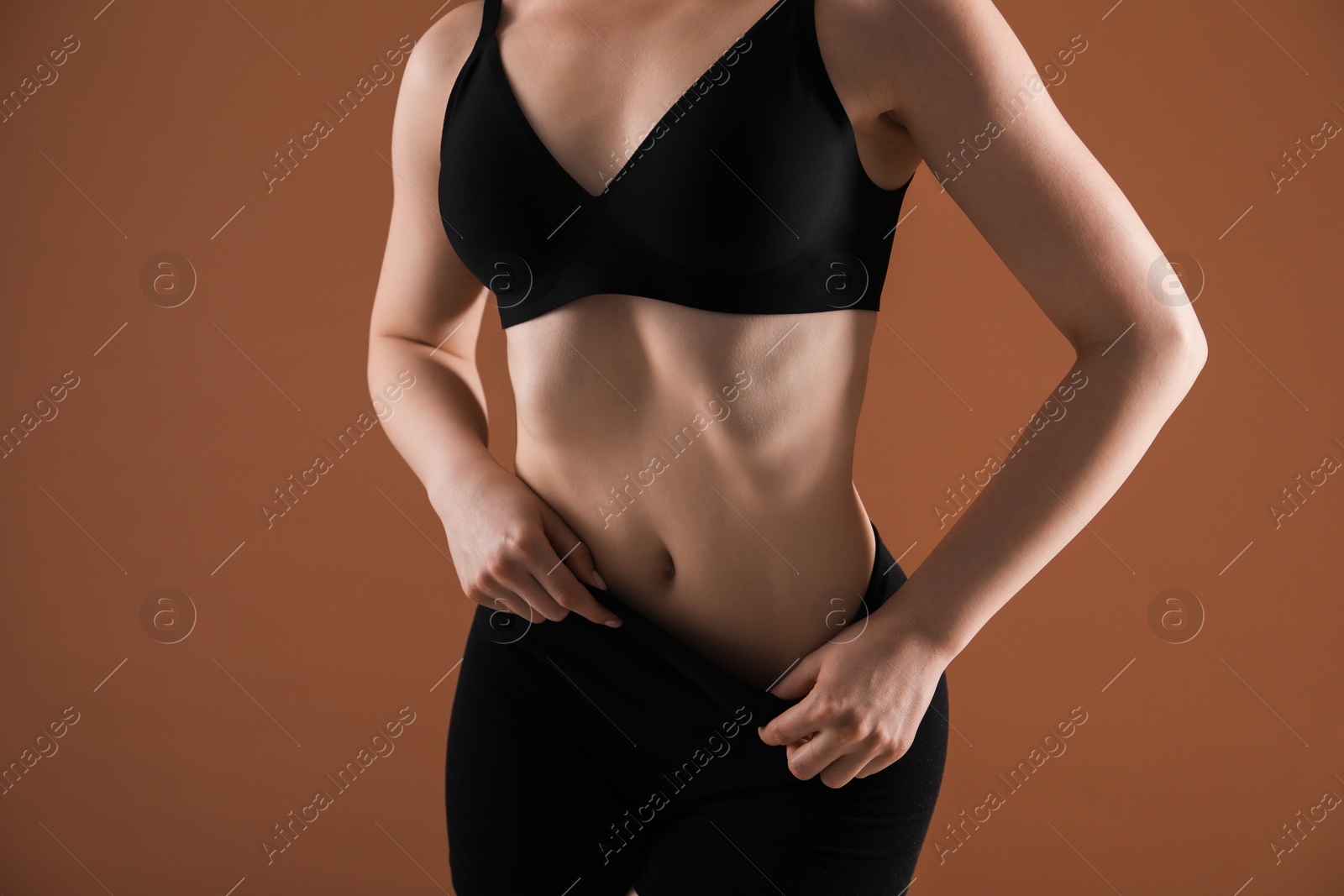 Attractive woman against brown background, closeup on belly Photo of Attractive woman against brown background, closeup on belly