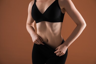 Photo of Attractive woman against brown background, closeup on belly