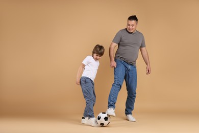 Photo of Father and his son playing football on beige background