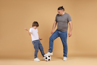 Photo of Father and his son playing football on beige background