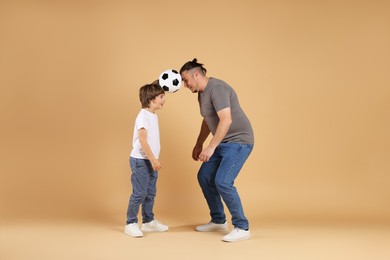 Photo of Father and his son playing football on beige background