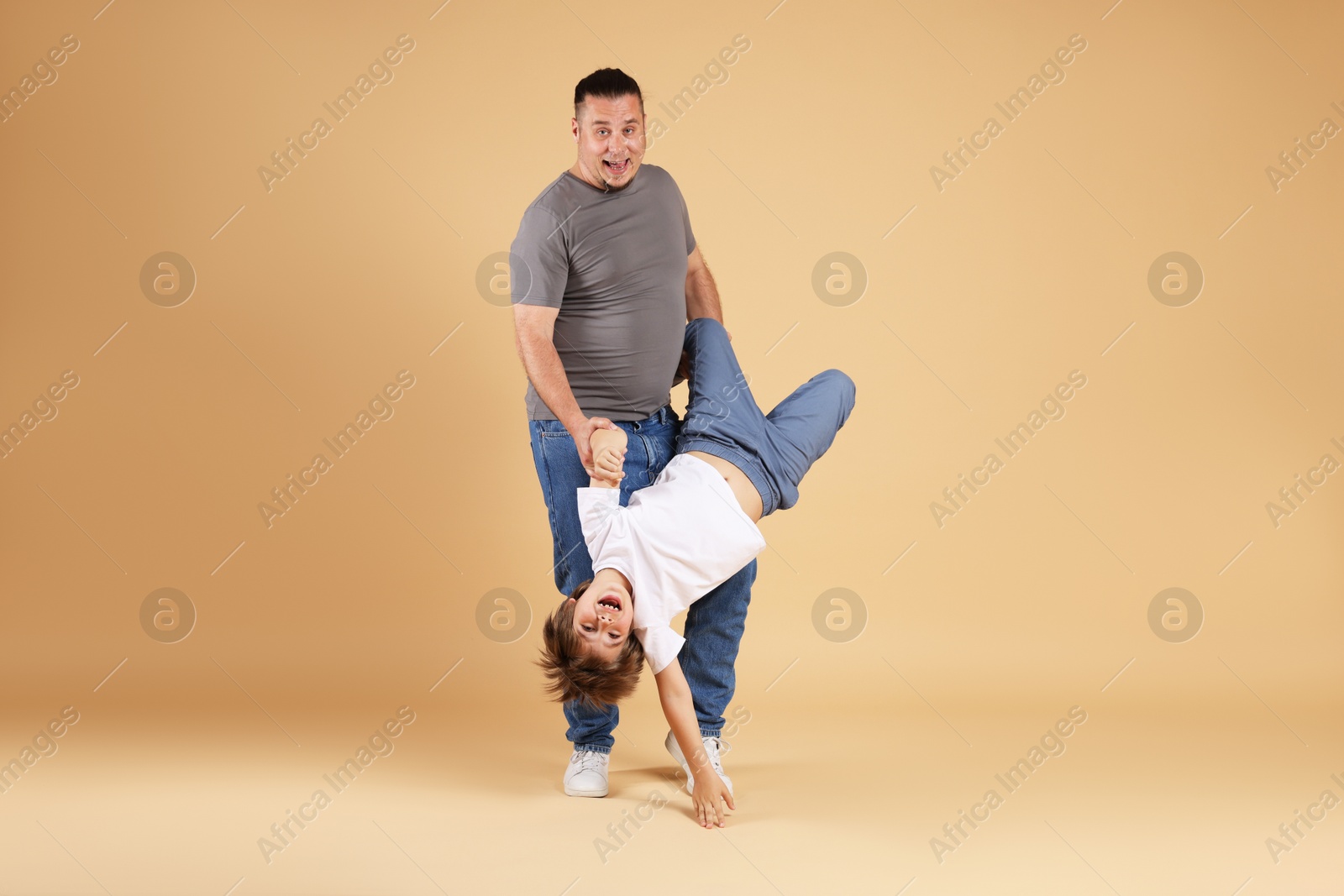 Father and his son having fun together on beige background Photo of Father and his son having fun together on beige background
