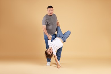 Photo of Father and his son having fun together on beige background