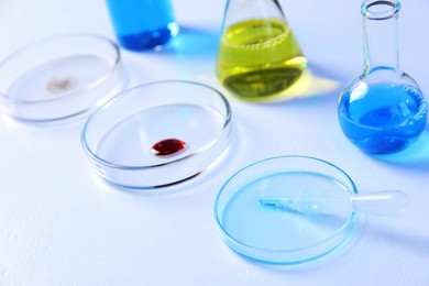 Photo of Petri dishes and flasks with samples on white background, closeup