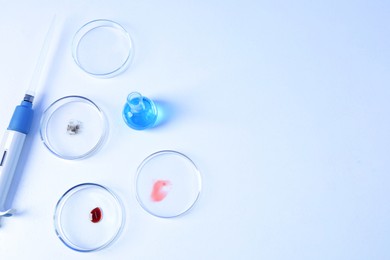 Photo of Petri dishes with samples, flask and micropipette on white background, flat lay. Space for text