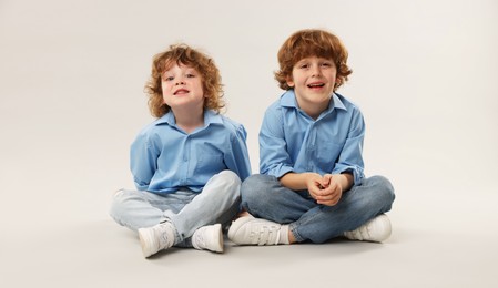 Photo of Cute little brothers together on light background