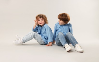 Photo of Cute little brothers together on light background