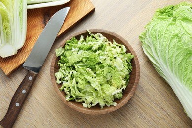 Photo of Fresh Chinese cabbages and knife on wooden table, flat lay