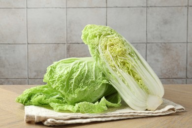 Photo of Whole and cut Chinese cabbages on wooden table