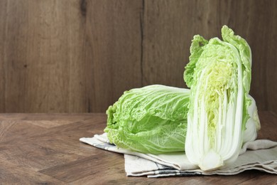Photo of Fresh Chinese cabbages on wooden table, space for text