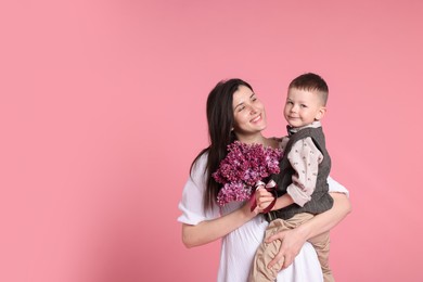 Photo of Mother and her son with bouquet of lilac flowers on pink background, space for text