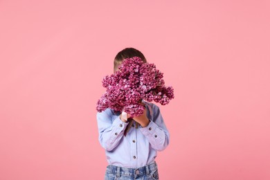 Photo of Little boy with bouquet of lilac flowers on pink background