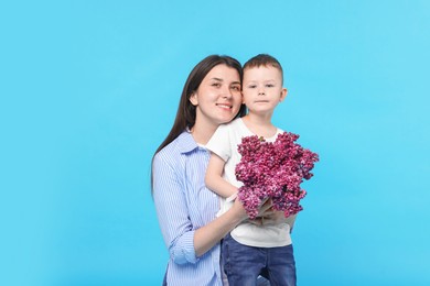 Photo of Mother and her son with bouquet of lilac flowers on light blue background