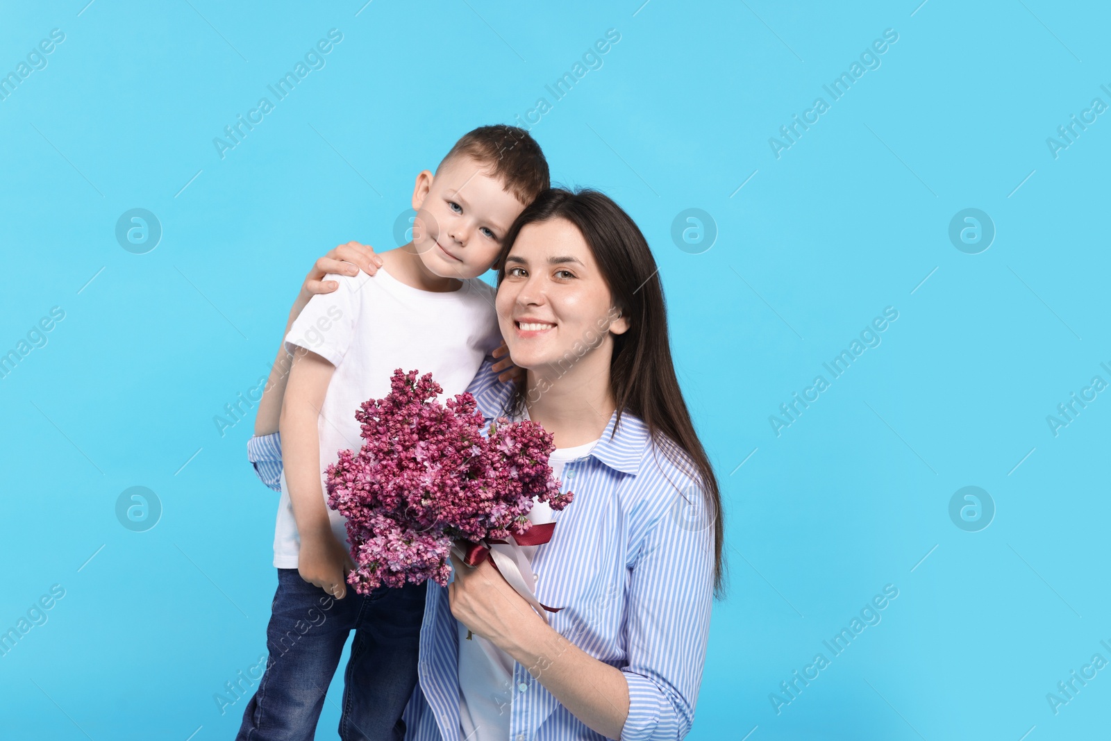 Mother and her son with bouquet of lilac flowers on light blue background, space for text Photo of Mother and her son with bouquet of lilac flowers on light blue background, space for text