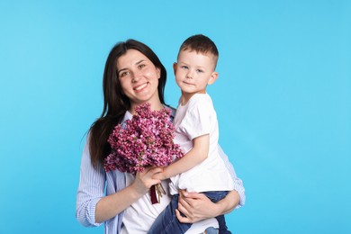 Photo of Mother and her son with bouquet of lilac flowers on light blue background