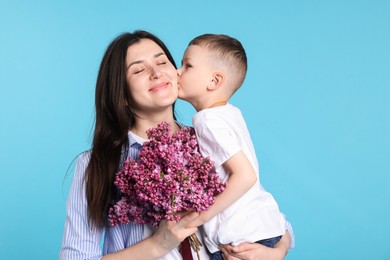 Photo of Mother and her son with bouquet of lilac flowers on light blue background