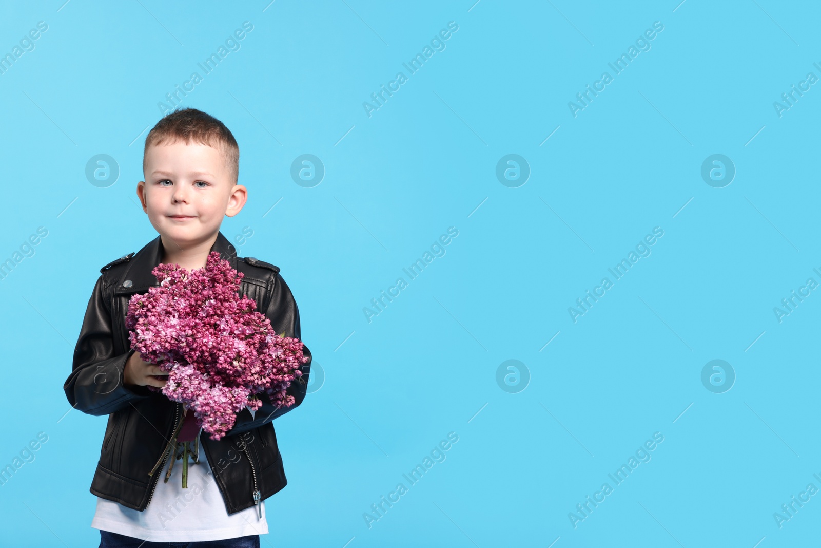 Little boy with bouquet of lilac flowers on light blue background, space for text Photo of Little boy with bouquet of lilac flowers on light blue background, space for text