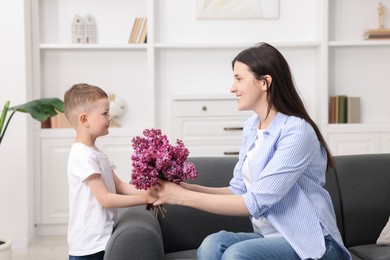 Photo of Mother and her son with bouquet of lilac flowers at home