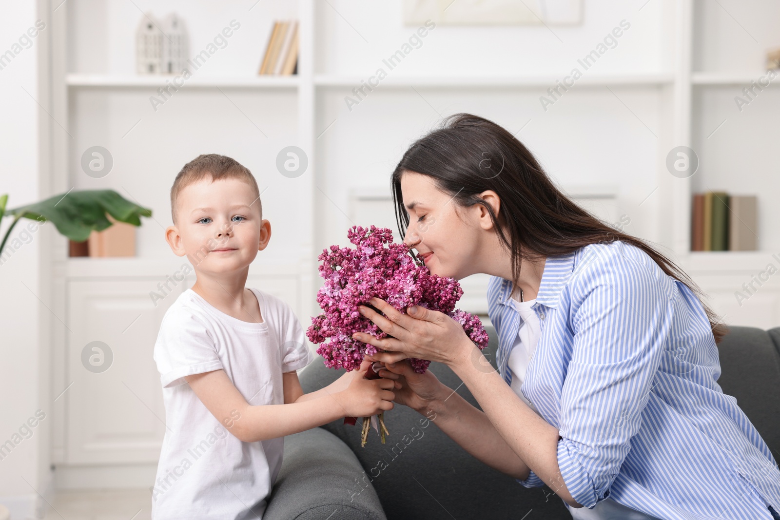 Mother and her son with bouquet of lilac flowers at home Photo of Mother and her son with bouquet of lilac flowers at home