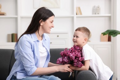 Photo of Mother and her son with bouquet of lilac flowers at home