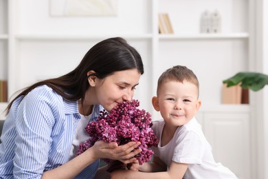 Photo of Mother and her son with bouquet of lilac flowers at home