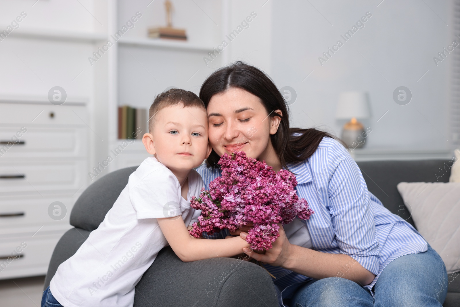 Mother and her son with bouquet of lilac flowers at home Photo of Mother and her son with bouquet of lilac flowers at home