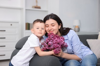 Photo of Mother and her son with bouquet of lilac flowers at home