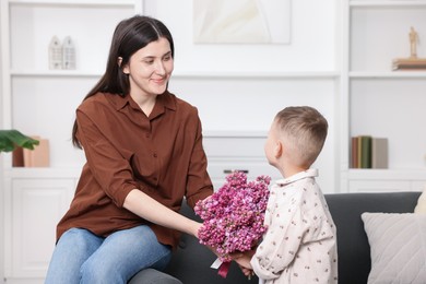 Photo of Mother and her son with bouquet of lilac flowers at home