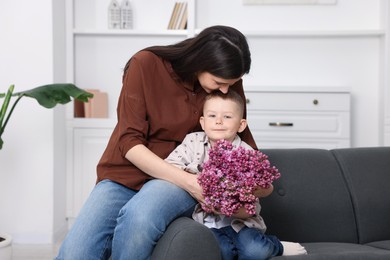 Photo of Mother and her son with bouquet of lilac flowers at home