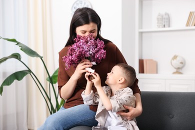 Photo of Mother and her son with bouquet of lilac flowers at home