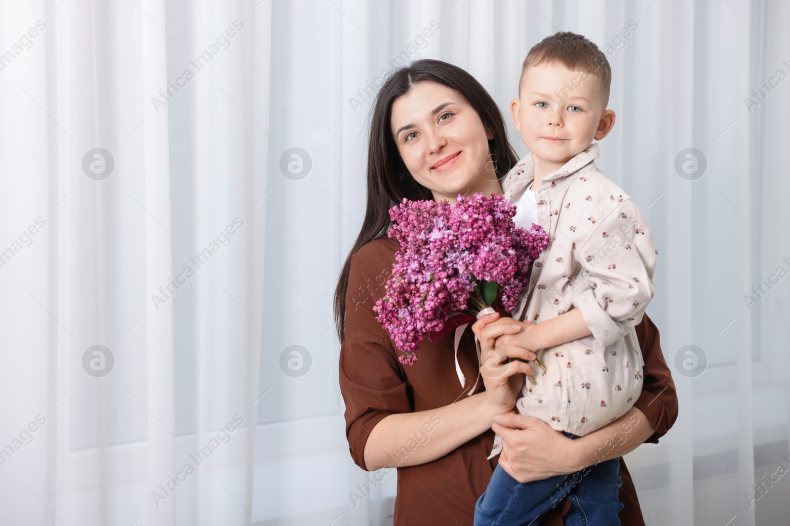 Mother and her son with bouquet of lilac flowers at home, space for text Photo of Mother and her son with bouquet of lilac flowers at home, space for text