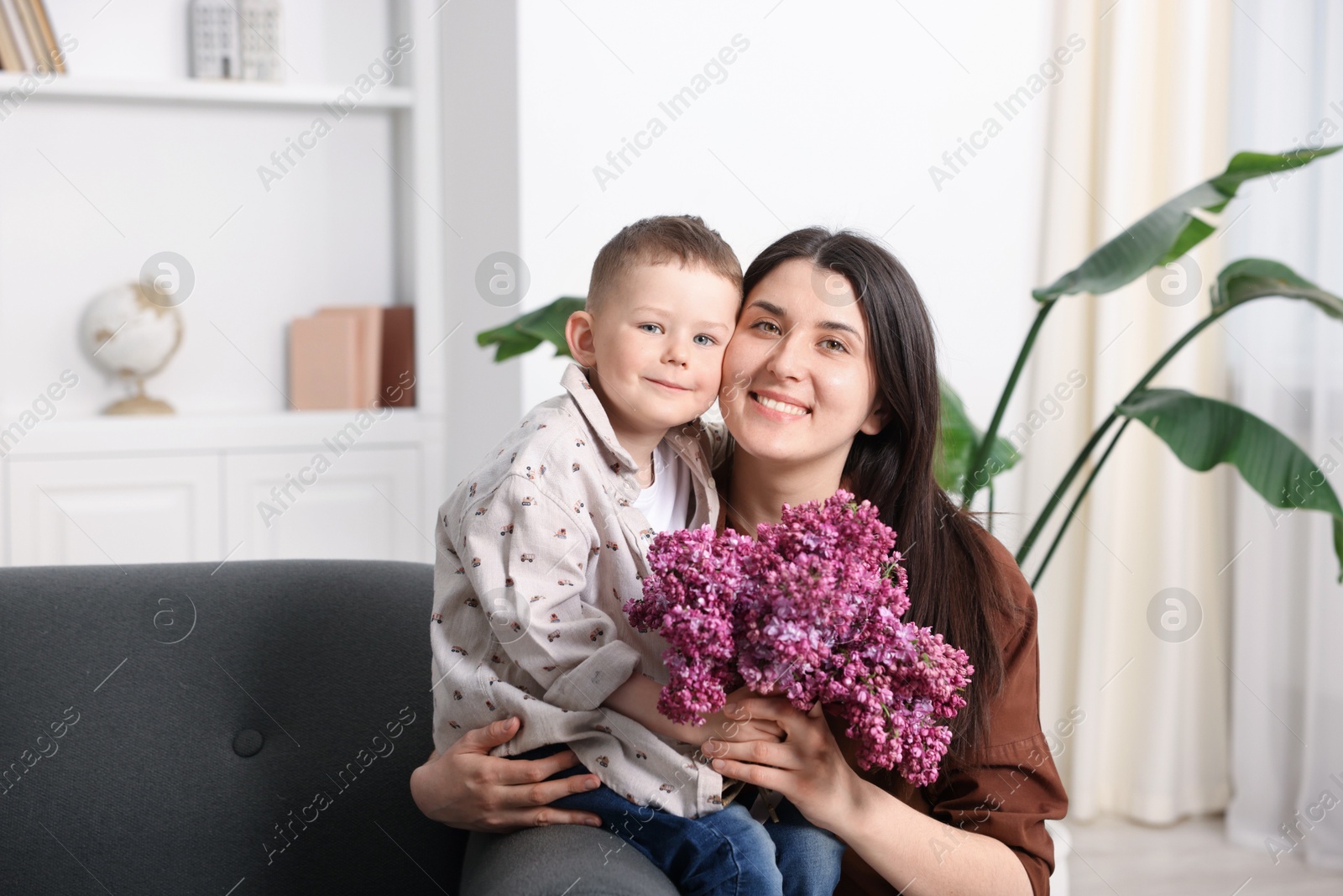 Mother and her son with bouquet of lilac flowers at home Photo of Mother and her son with bouquet of lilac flowers at home