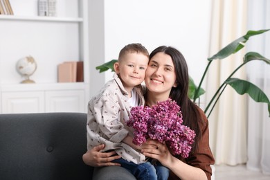 Photo of Mother and her son with bouquet of lilac flowers at home
