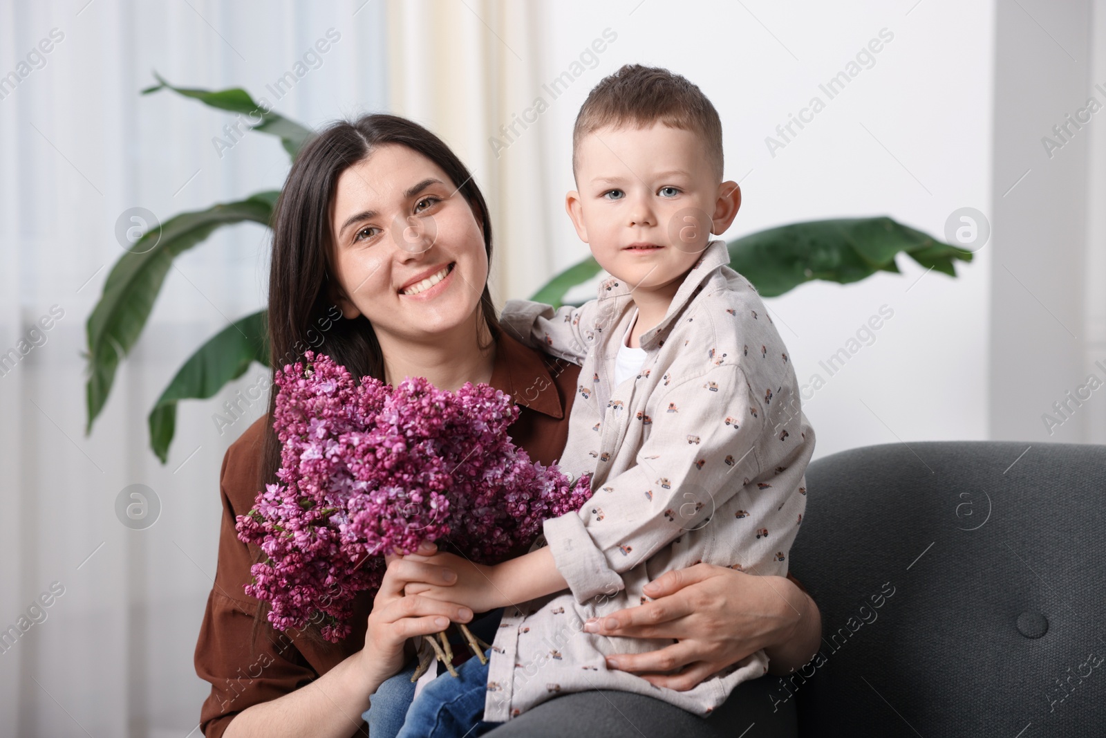 Mother and her son with bouquet of lilac flowers at home Photo of Mother and her son with bouquet of lilac flowers at home