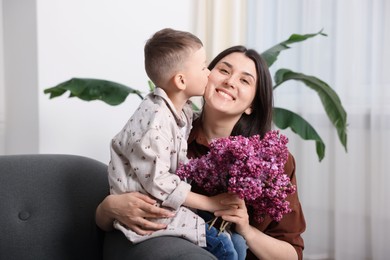 Photo of Mother and her son with bouquet of lilac flowers at home