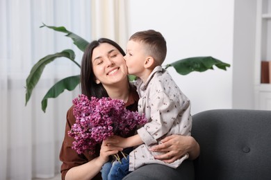 Photo of Mother and her son with bouquet of lilac flowers at home