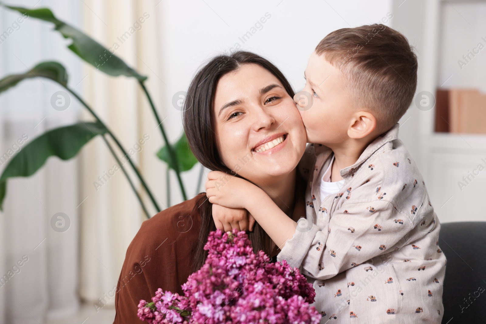 Mother and her son with bouquet of lilac flowers at home Photo of Mother and her son with bouquet of lilac flowers at home
